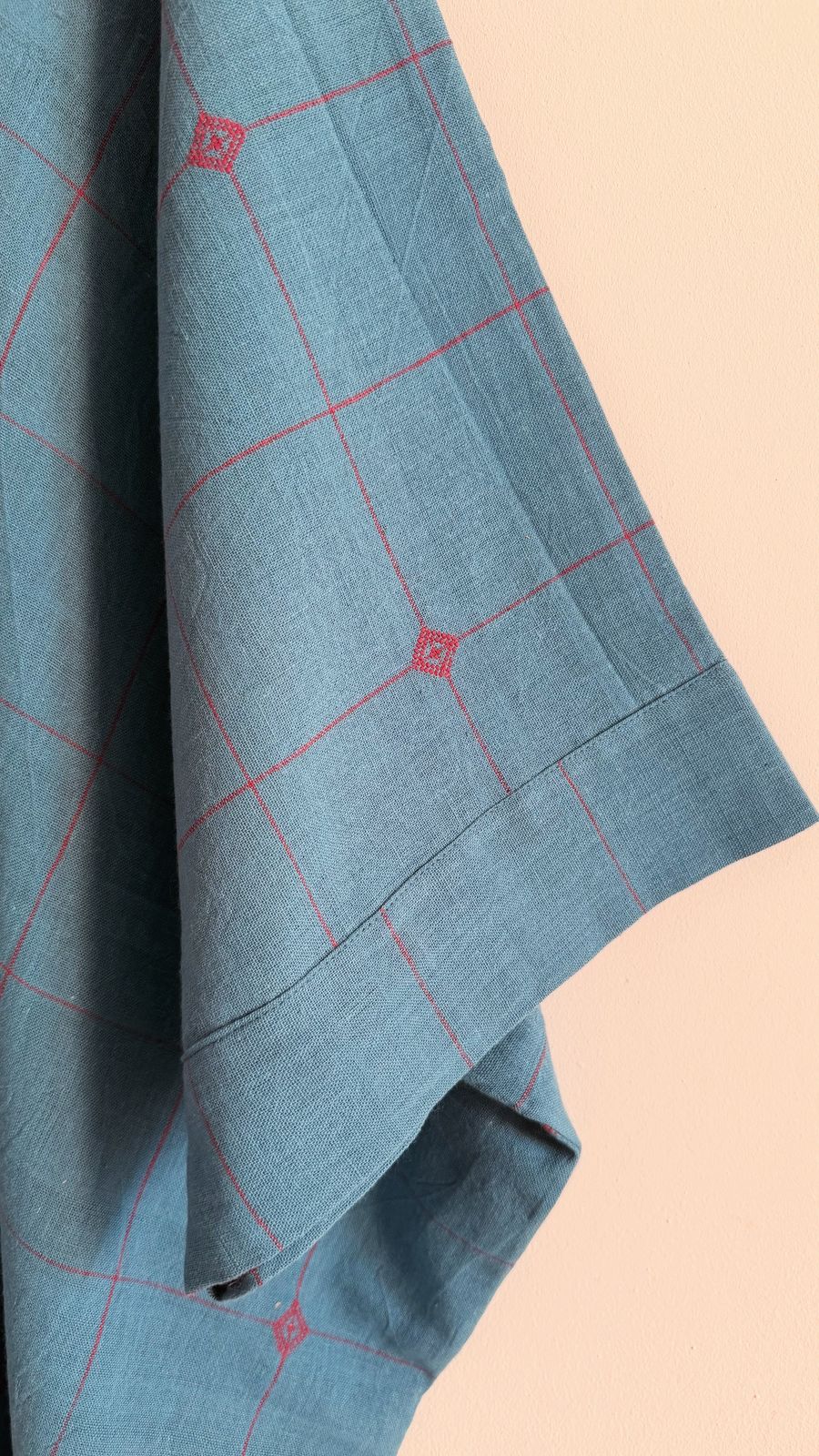Close-up of blue garnet handwoven cotton kaftan featuring fine garnet check lines and sleeve finish