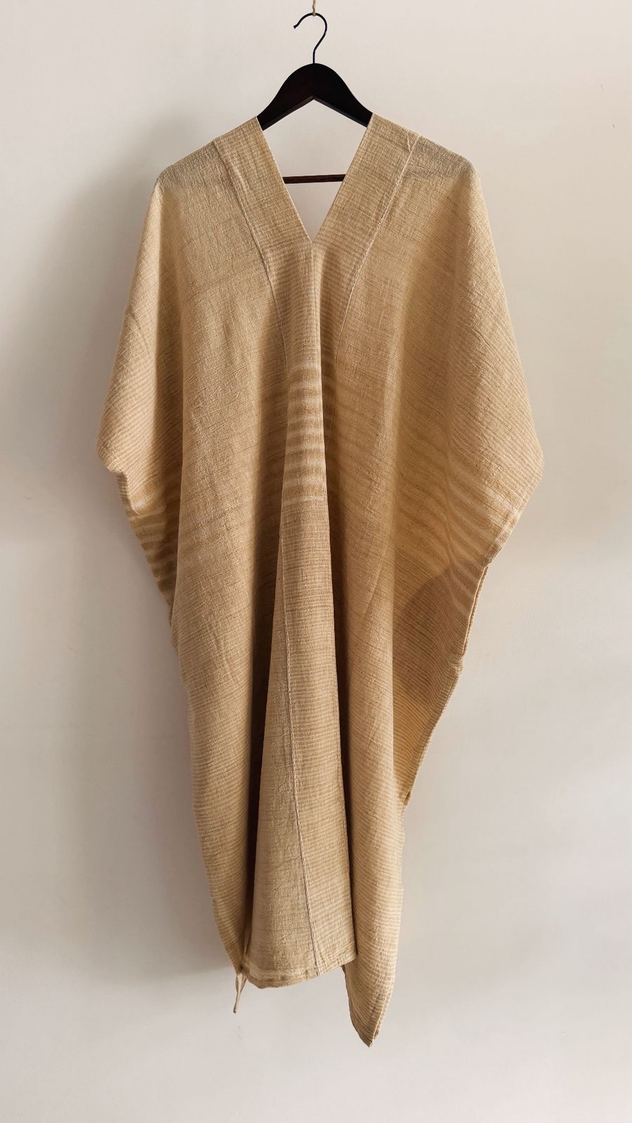 Front view of the Clove Kaftan in Oat Butter, made in handwoven cotton with a deep V-neckline, hand embroidery detailing, and subtle woven stripes.