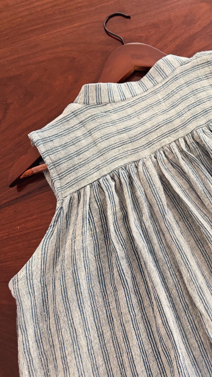 Back view of sleeveless handwoven striped cotton top with gathered yoke.