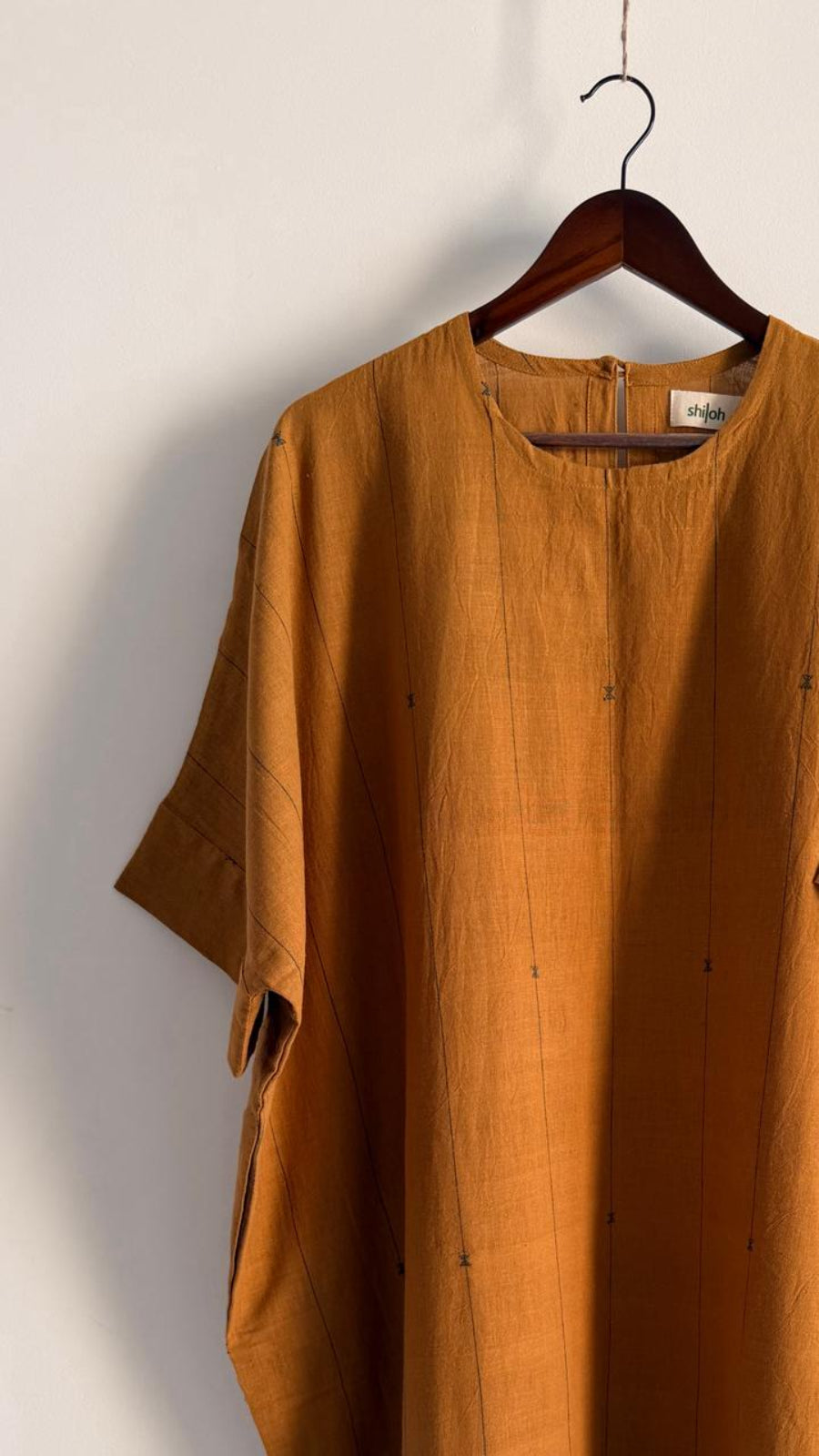 Close-up of handwoven khadi dress showing soft round neckline and subtle motifs