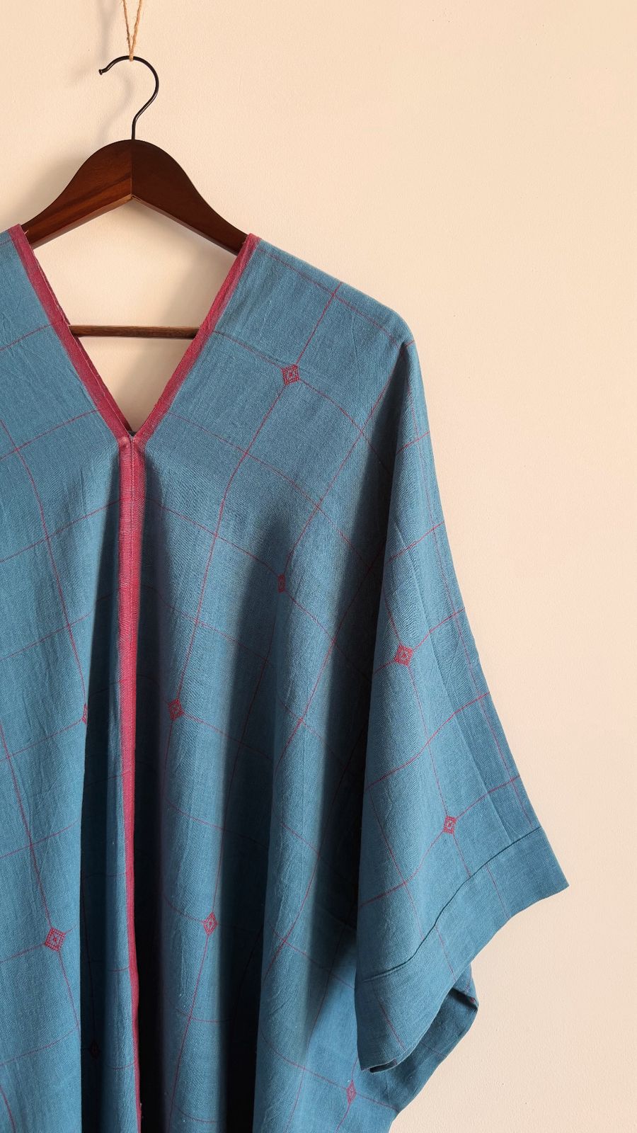 Close up of sage Kaftan in blue garnet handwoven cotton with subtle check pattern and magenta neckline detail