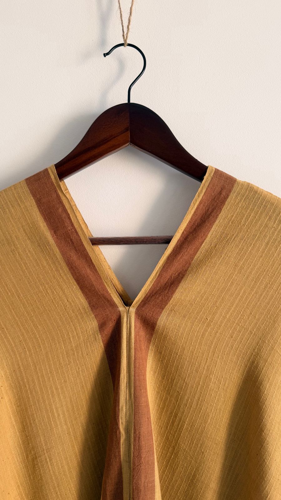 Close-up of Sage Kaftan neckline showing bark border detail on handwoven ochre fabric