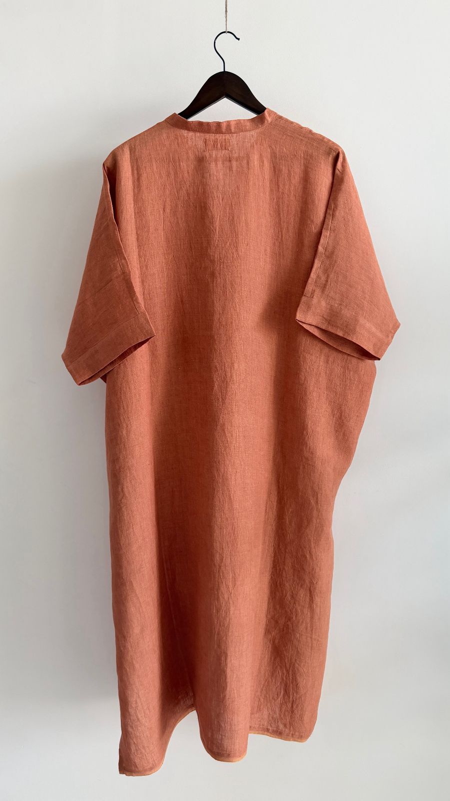 Back view of handwoven tangerine linen dress with relaxed drape and soft structure