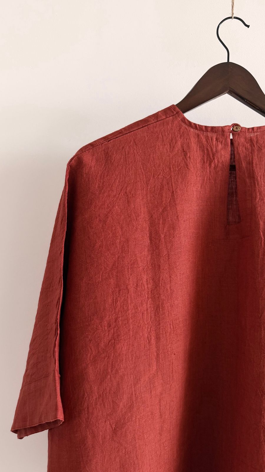 Back view of handwoven linen top in burnt berry with subtle opening and button detail