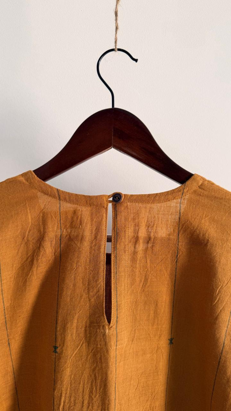 Back detail of amber pine handwoven cotton dress with slit and button closure