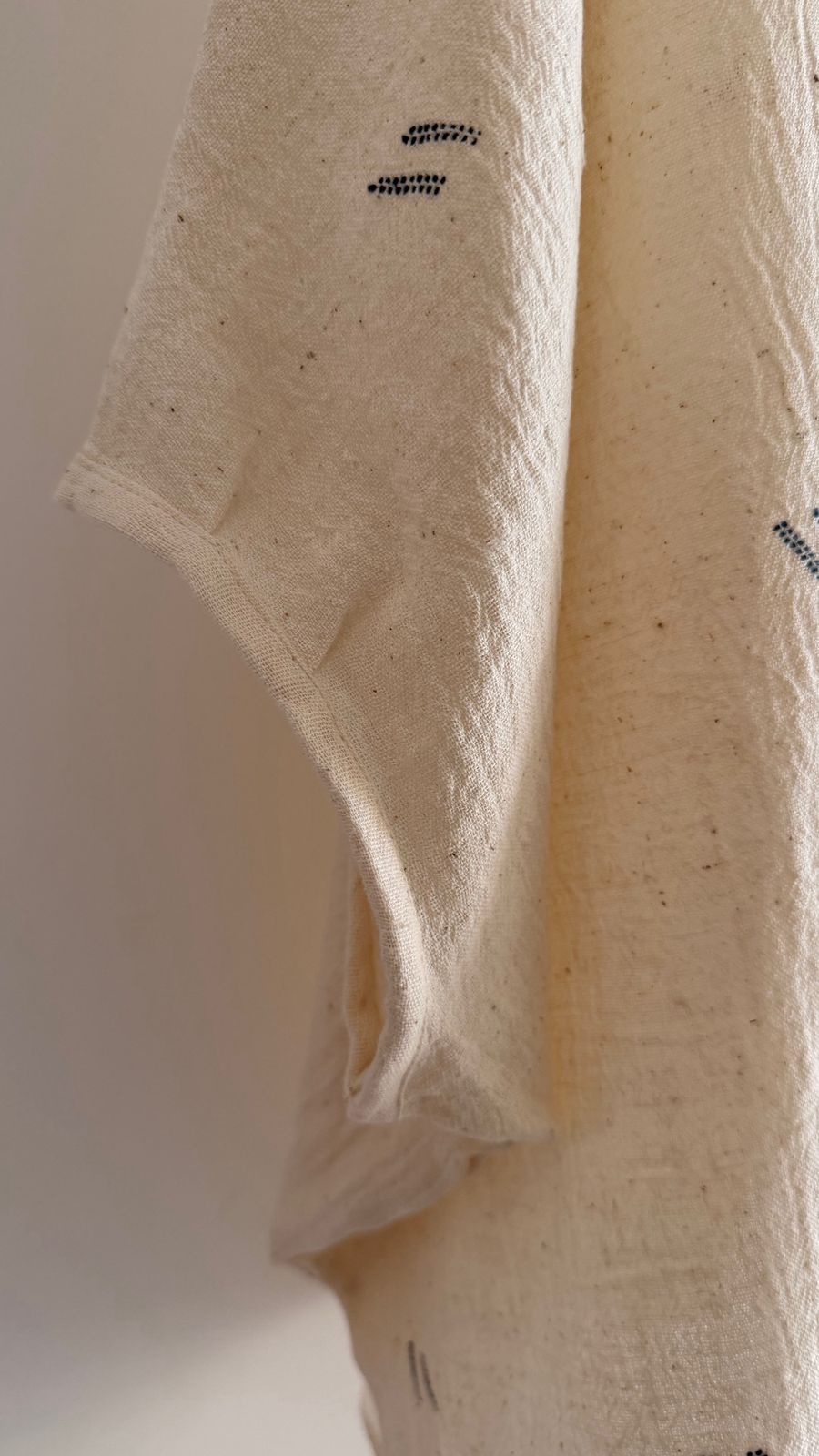 Close-up of handwoven cotton sleeve with subtle ink motifs and soft textured weave