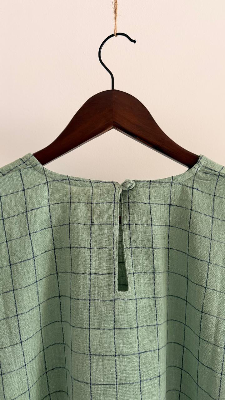 Back view of pale teal handwoven cotton top with grid weave, wide sleeves, and button closure.
