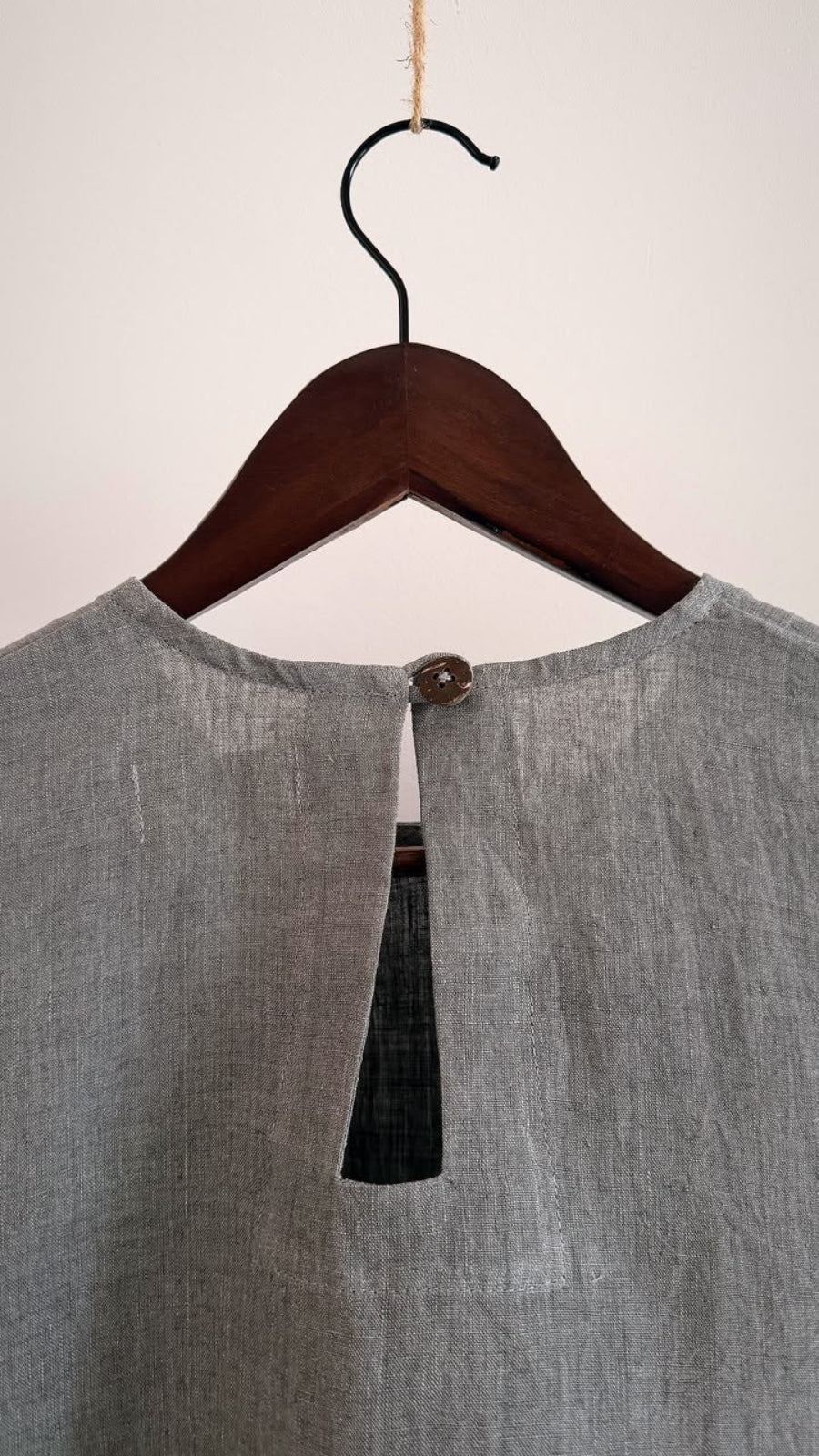 Close-up of the back keyhole opening with a coconut shell button on the Elm ash grey handwoven linen top.