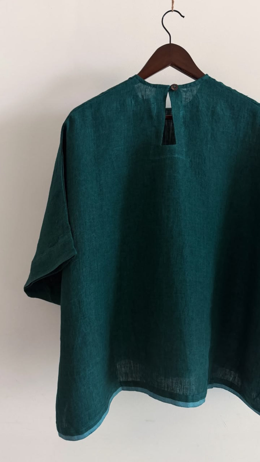 Back view of the Elm handwoven linen top in forest green featuring a keyhole opening with a coconut shell button.