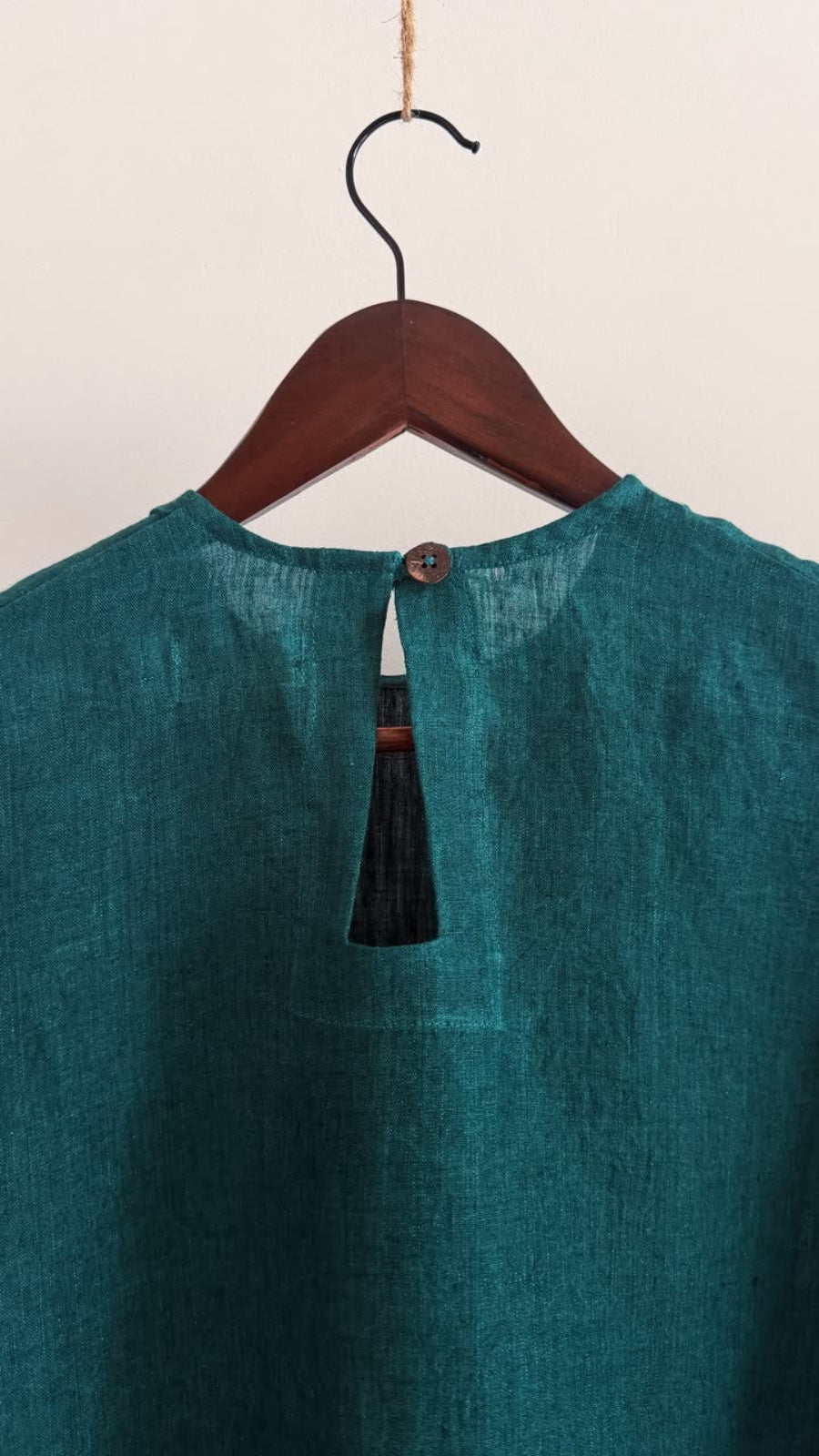 Close-up of the coconut shell button and keyhole back opening on the Elm forest green handwoven linen top.