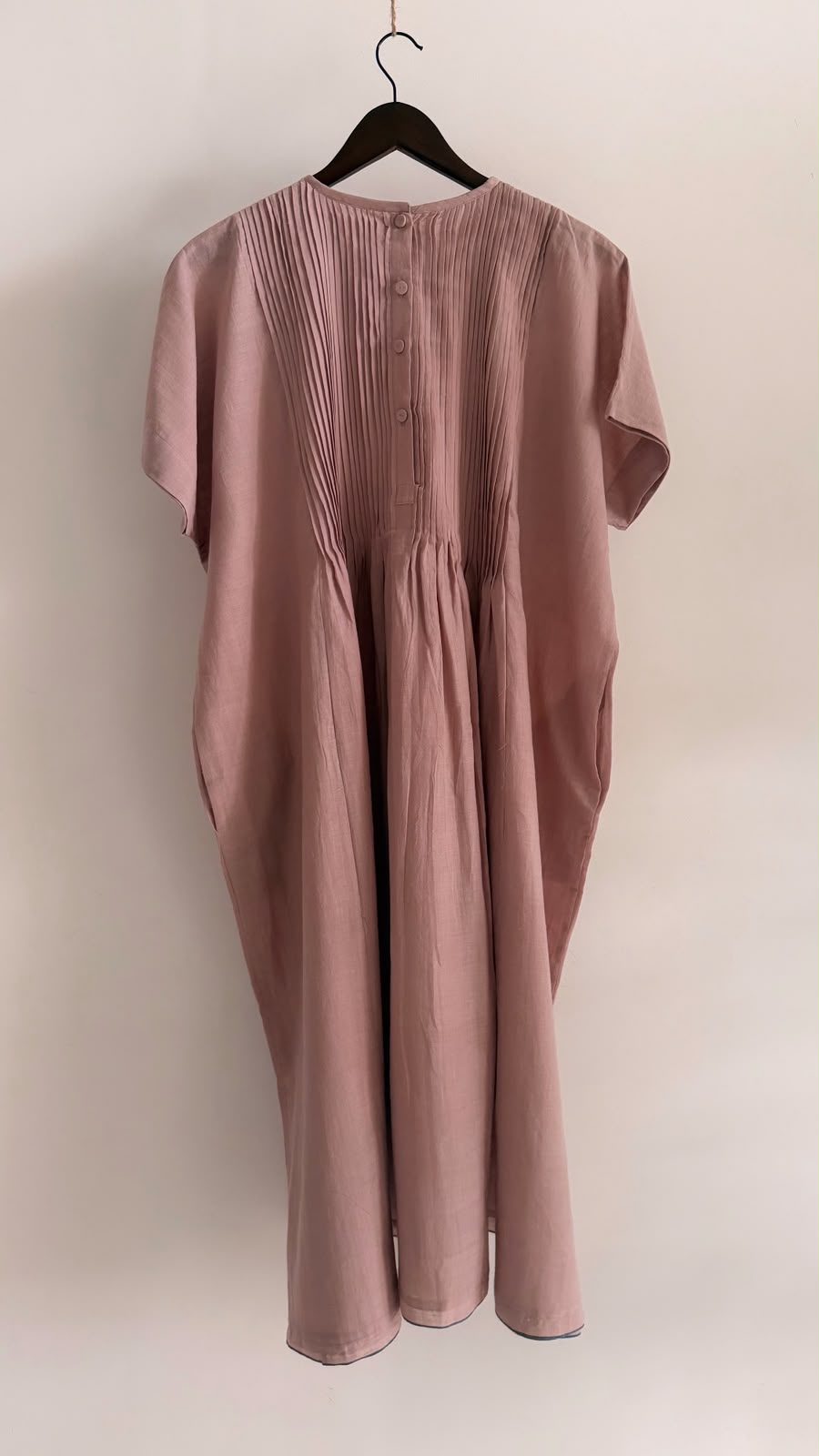 Back view of muted mauve handwoven khadi dress featuring pintucks and fabric-covered buttons.