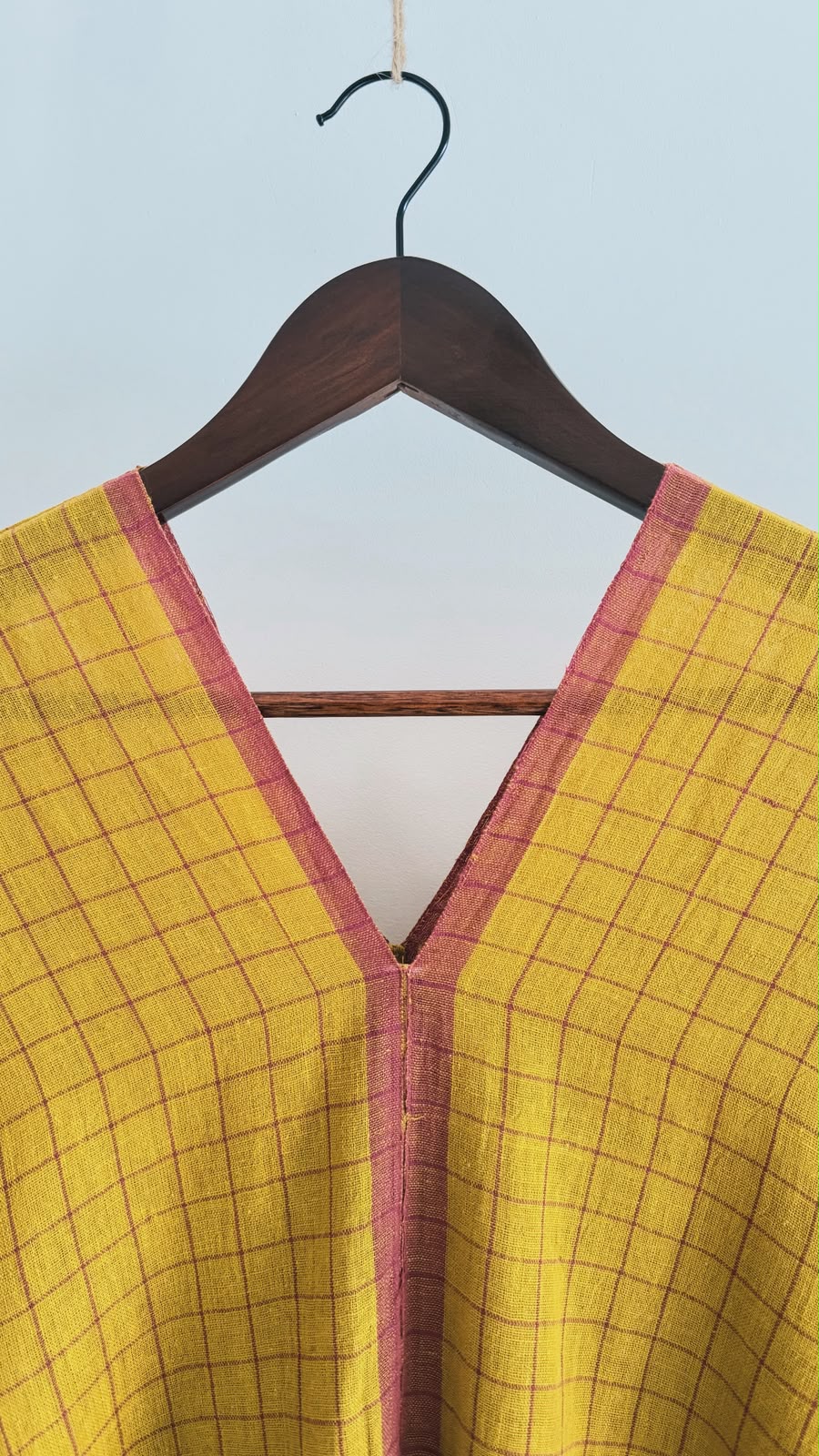 Close-up of the Sage handwoven cotton kaftan in earthen mustard featuring windowpane checks and a matching V-neck border.