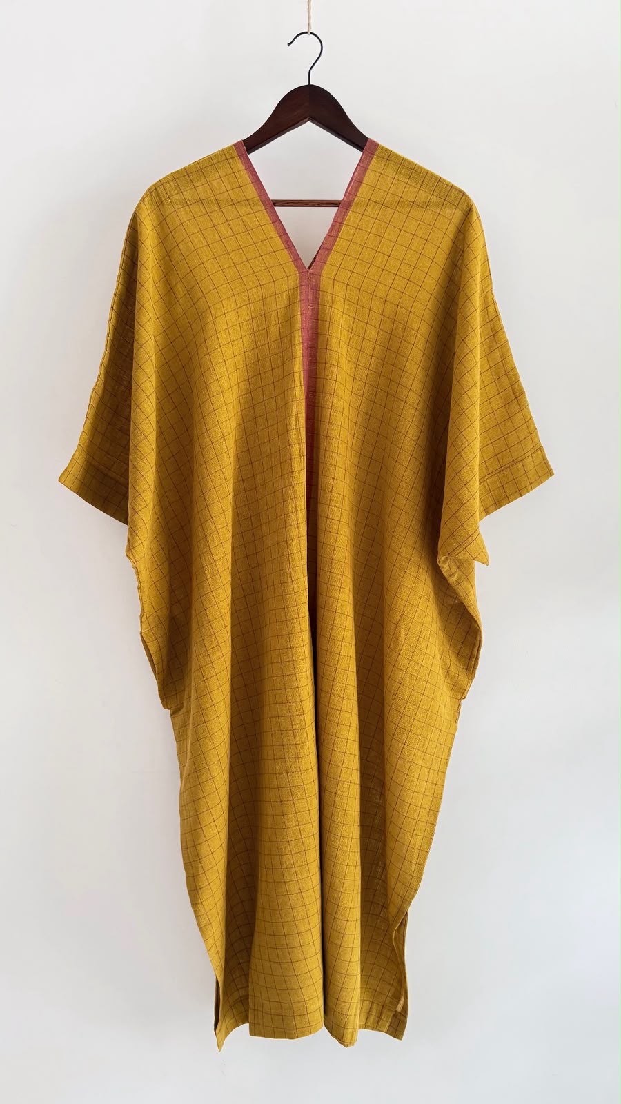 Full-length Sage kaftan in earthen mustard, crafted from handwoven cotton with windowpane checks, a matching V-neck border, and a free-flowing silhouette.