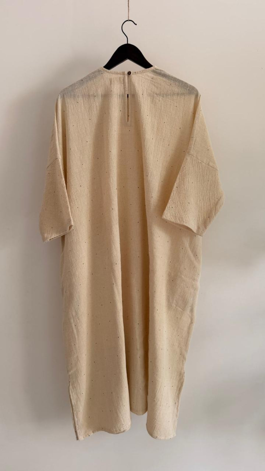 Full back view of handwoven kora cotton dress with wide sleeves, ink-speck detailing, and back button closure.